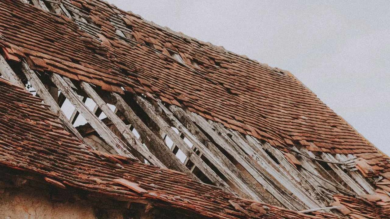Storm-damaged roof with lifted and broken shingles in Missouri