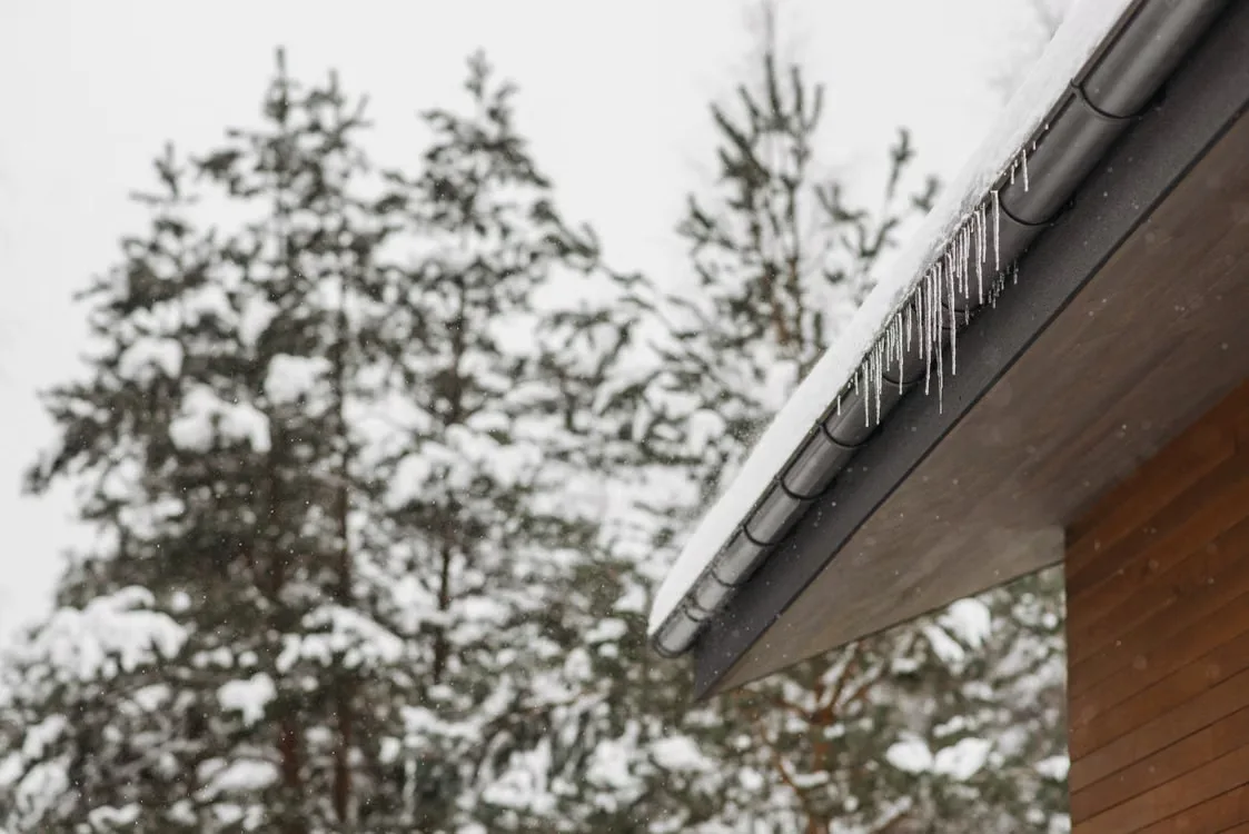 Ice dam frozen on a metal gutter at a roof's edge
